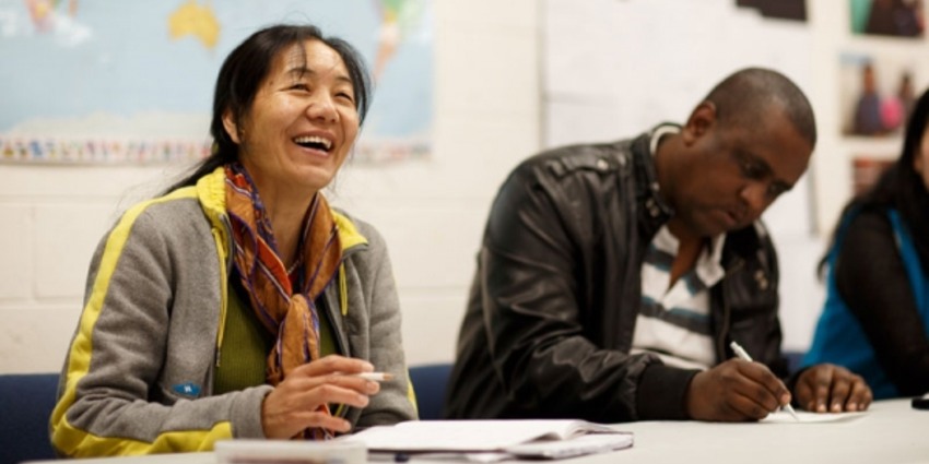 Two adults studying at a table in a classroom.