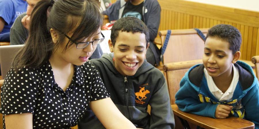 A female college student talks to two middle-school aged boys.