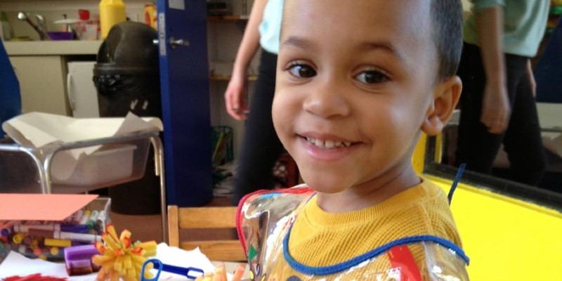 Smiling child in a yellow shirt and a plastic smock