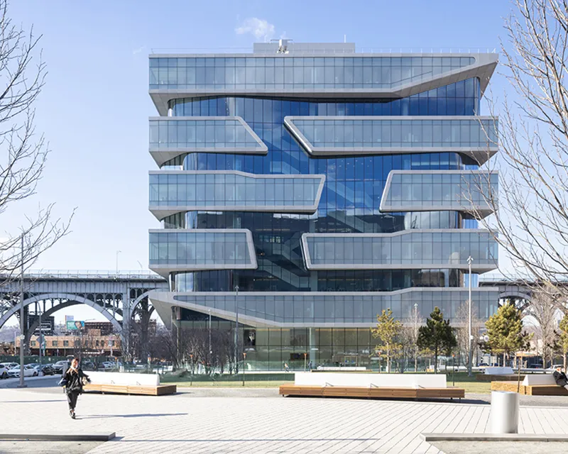 Facade of Kravis Hall against a blue sky in front of the Riverside Dr viaduct.