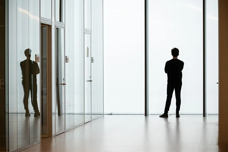 A light-filled hallway and a student standing at a window. 