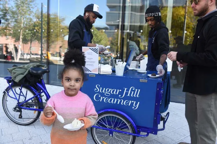 A little kid enjoys a scoop of complimentary ice cream from Sugar Hill Creamery. 
