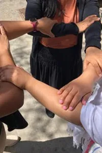 Three people hold on to each other in a triangle