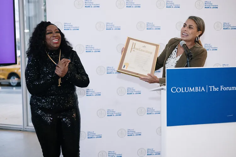A woman standing on the left wins an award and a woman on the right is handing the award to her. 