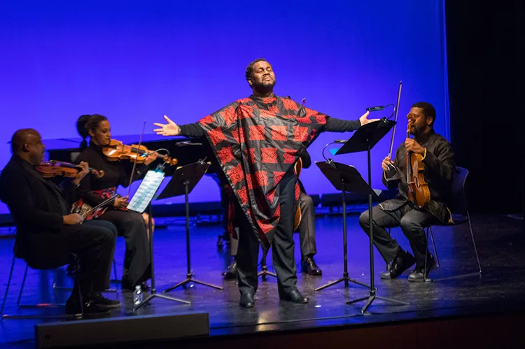 Man performing at the front of an orchestra. 