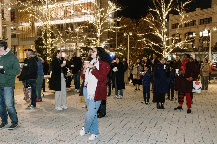 Woman enjoying the holiday lights decorating the trees on The Plaza on Columbia's Manhattanville campus.