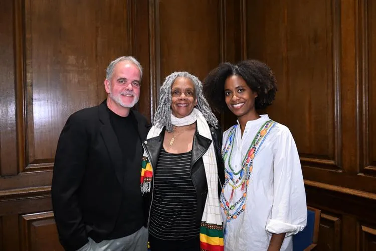 Three people stand smiling and posing for a photo