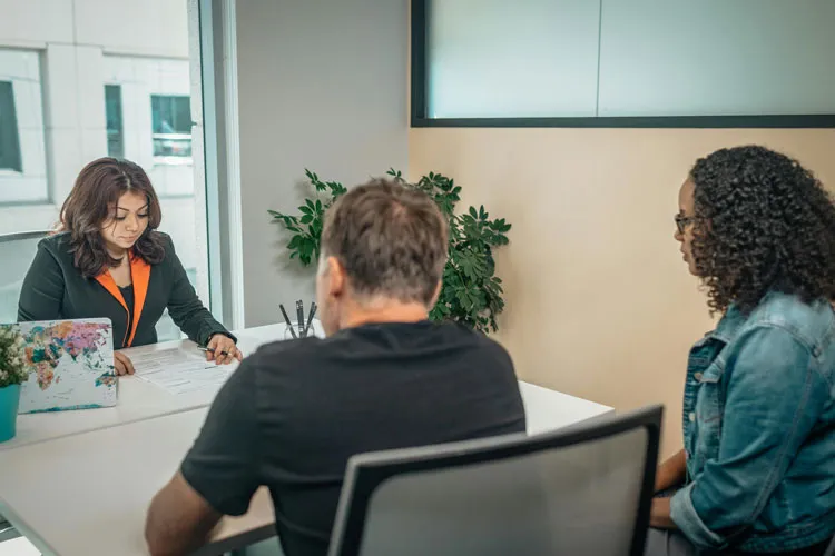 Employee talking with couple over a desk. 