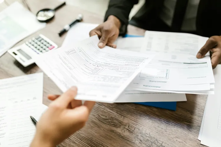 Someone passing a tax form to someone else over a desk.