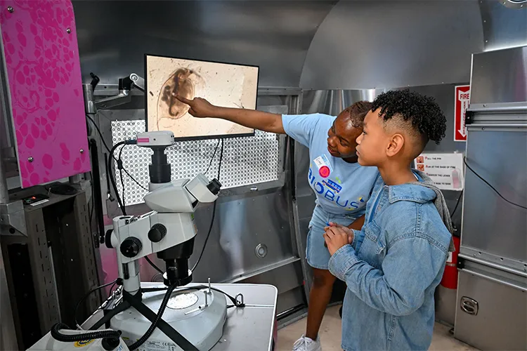 A kid and adult look at microscopic life. 