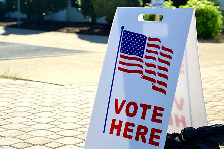 A sandwich board reading "Vote Here"