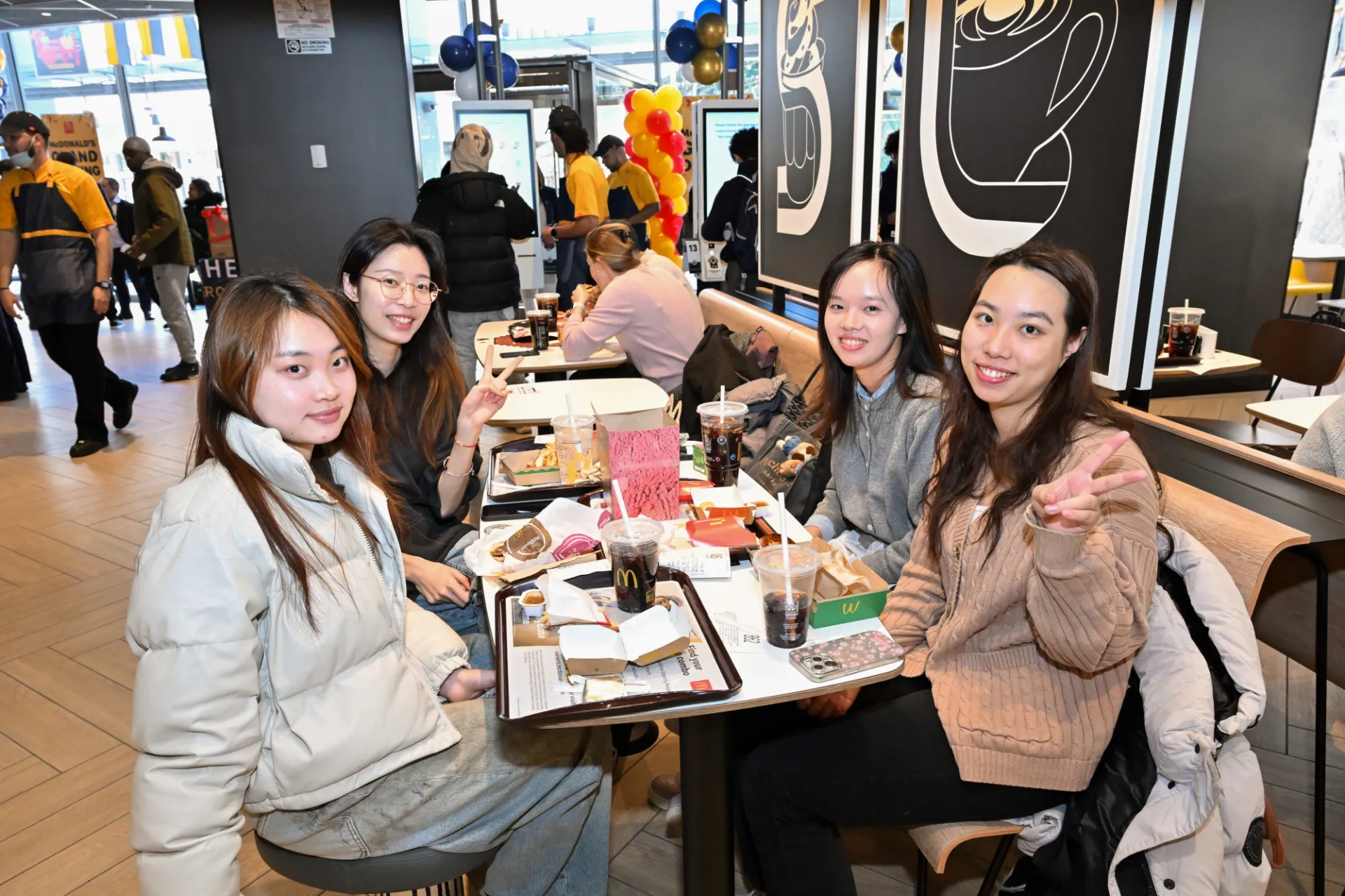 McDonald's customers smile at the camera as they eat lunch.