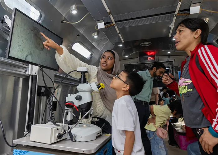 Kids and parents look in awe at a micoscope reading.