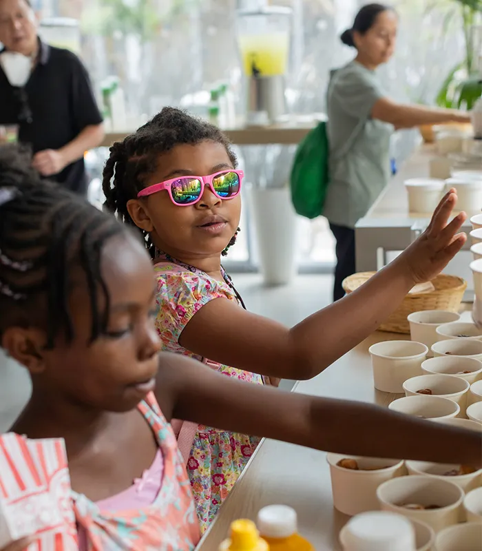 A child in sunglasses reaches for pretzel bites. 