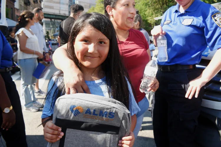 A youngster poses with her new backpack at the annual back-to-school event in West Harlem. Photo credit: Susan Farley