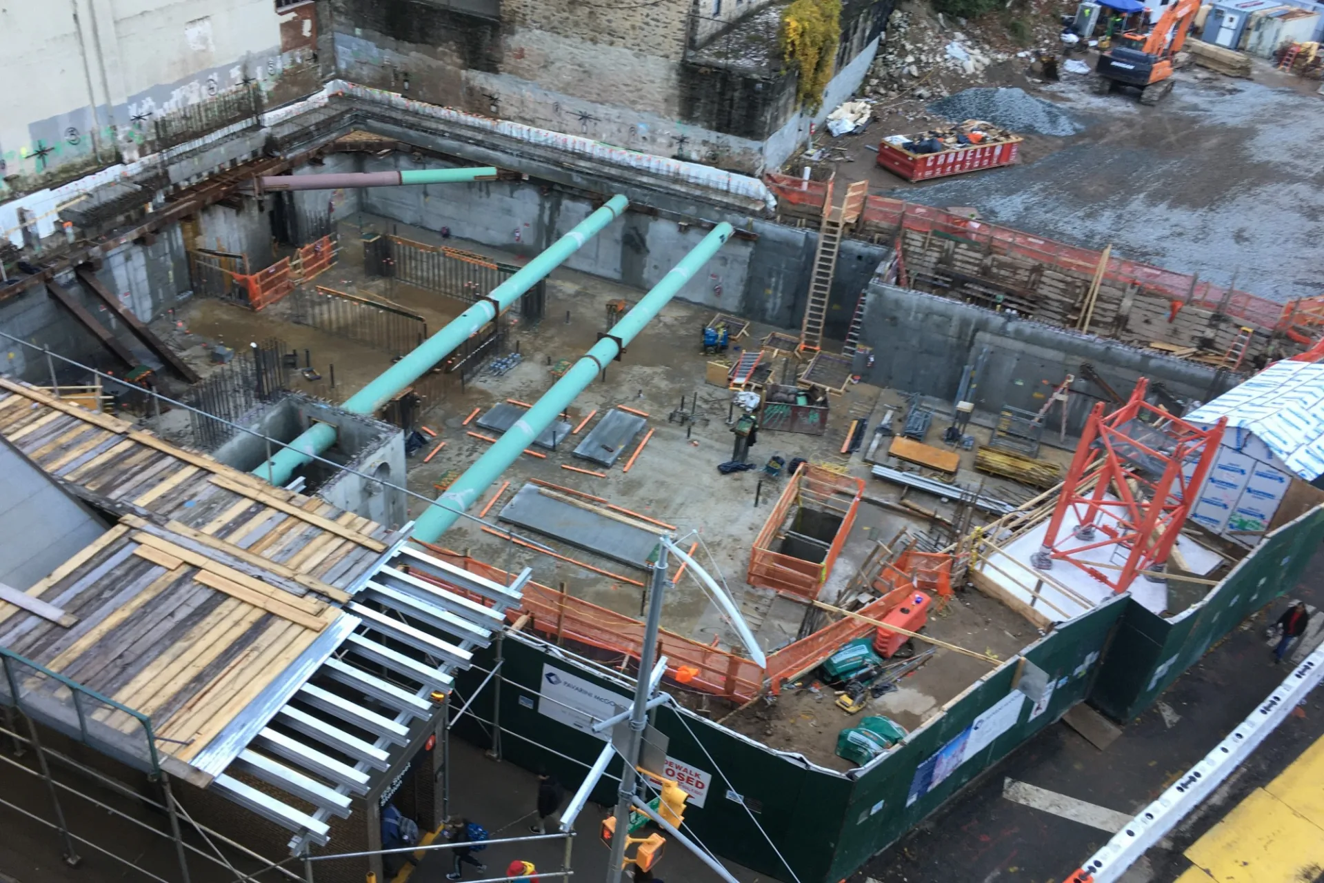 A aerial view of the 600 W. 125th Street construction site, full of materials and large green pipes running overhead.