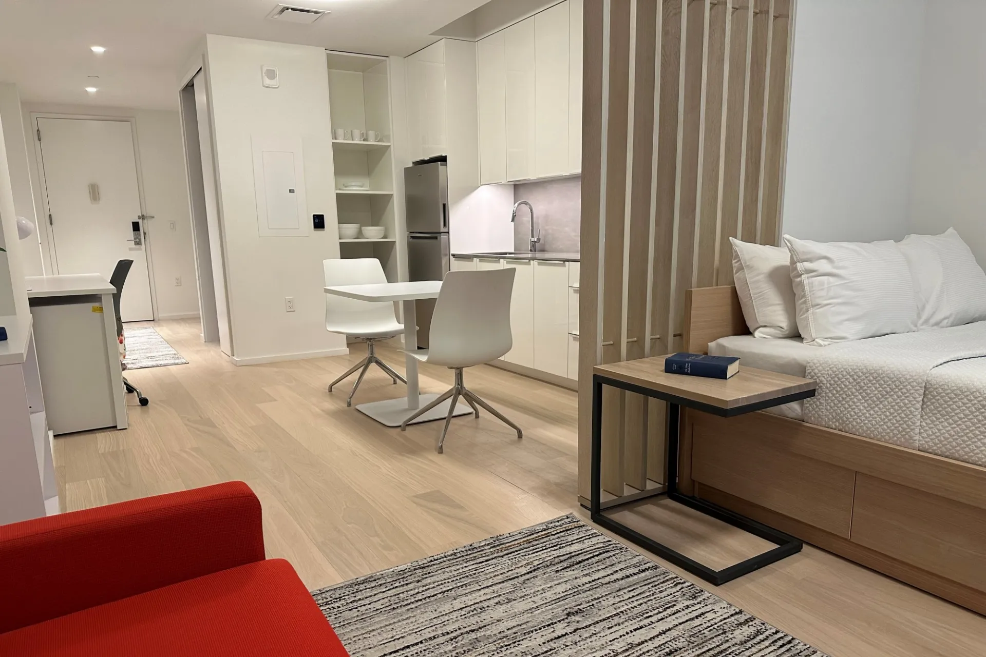 A finished apartment in the new 600 W. 125th Street building with neutral colored furnishings and a bright red couch.