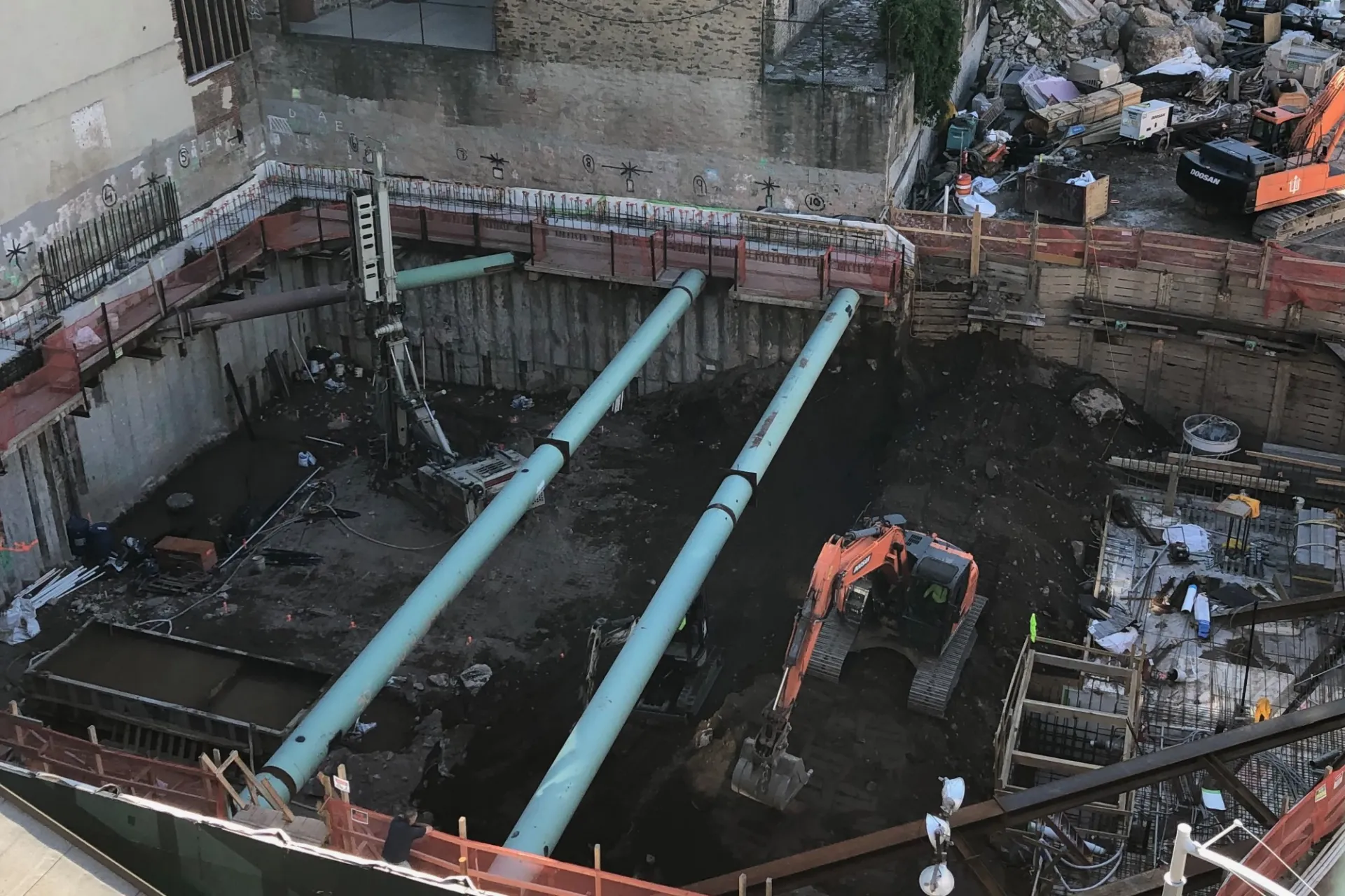 A view of the 600 W. 125th Street construction site with steel beams running across a dirt pit. 