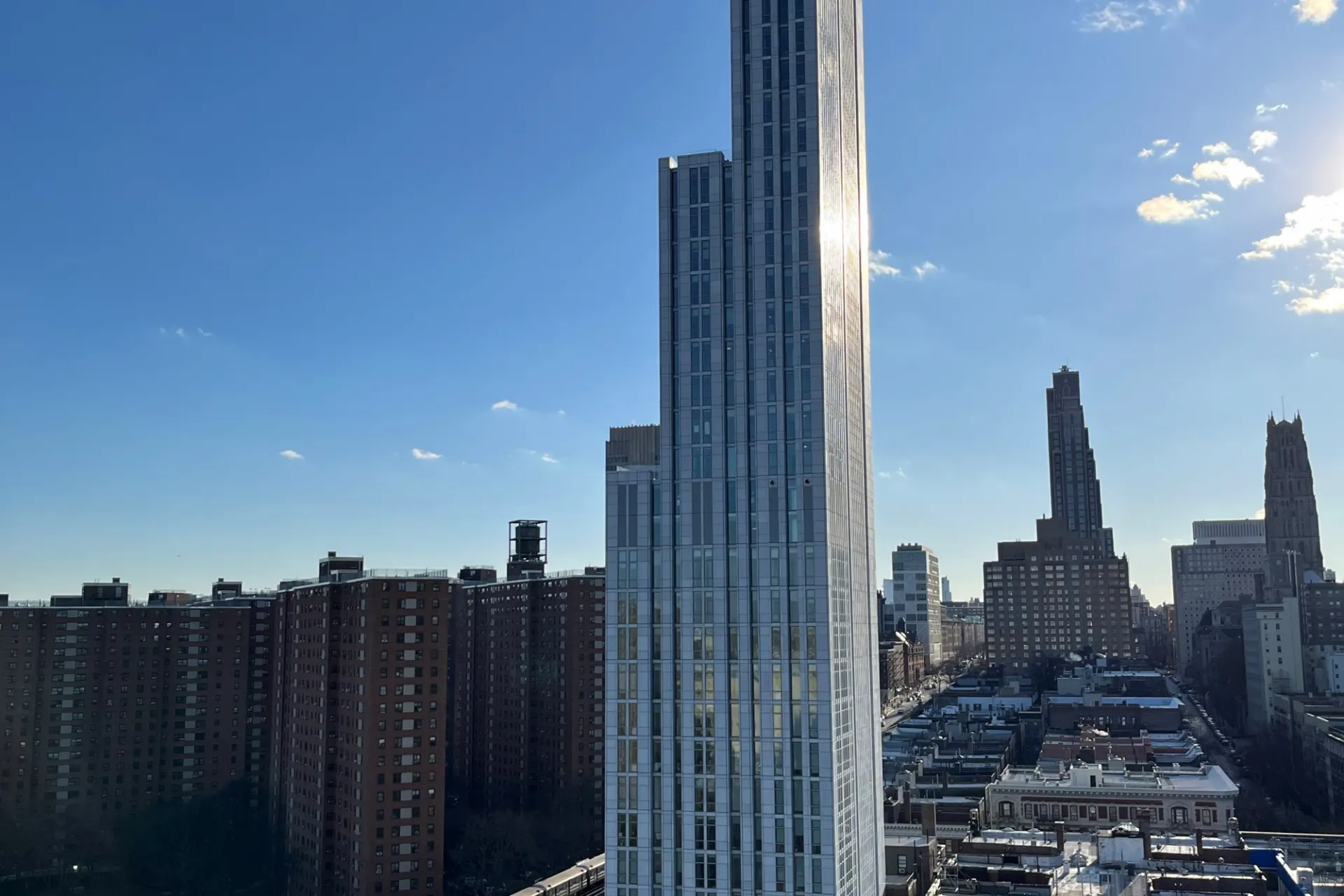 A view of the upper floors of 600 W. 125th Street on a sunny day with Morningside Heights in the background. 