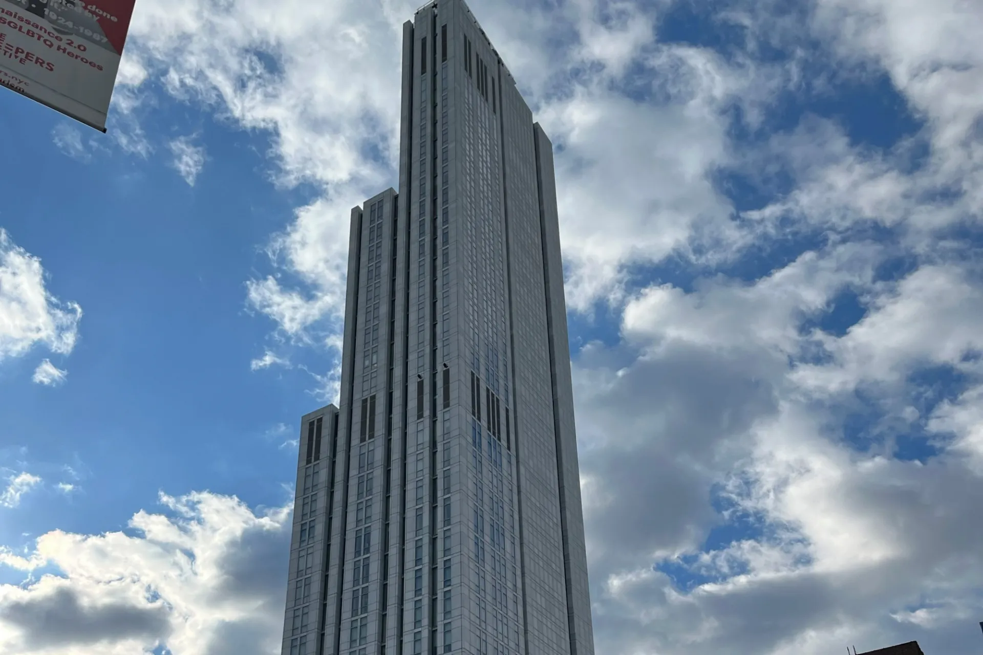 A view of the upper floors of 600 W. 125th Street on a sunny day with clouds in the sky. 