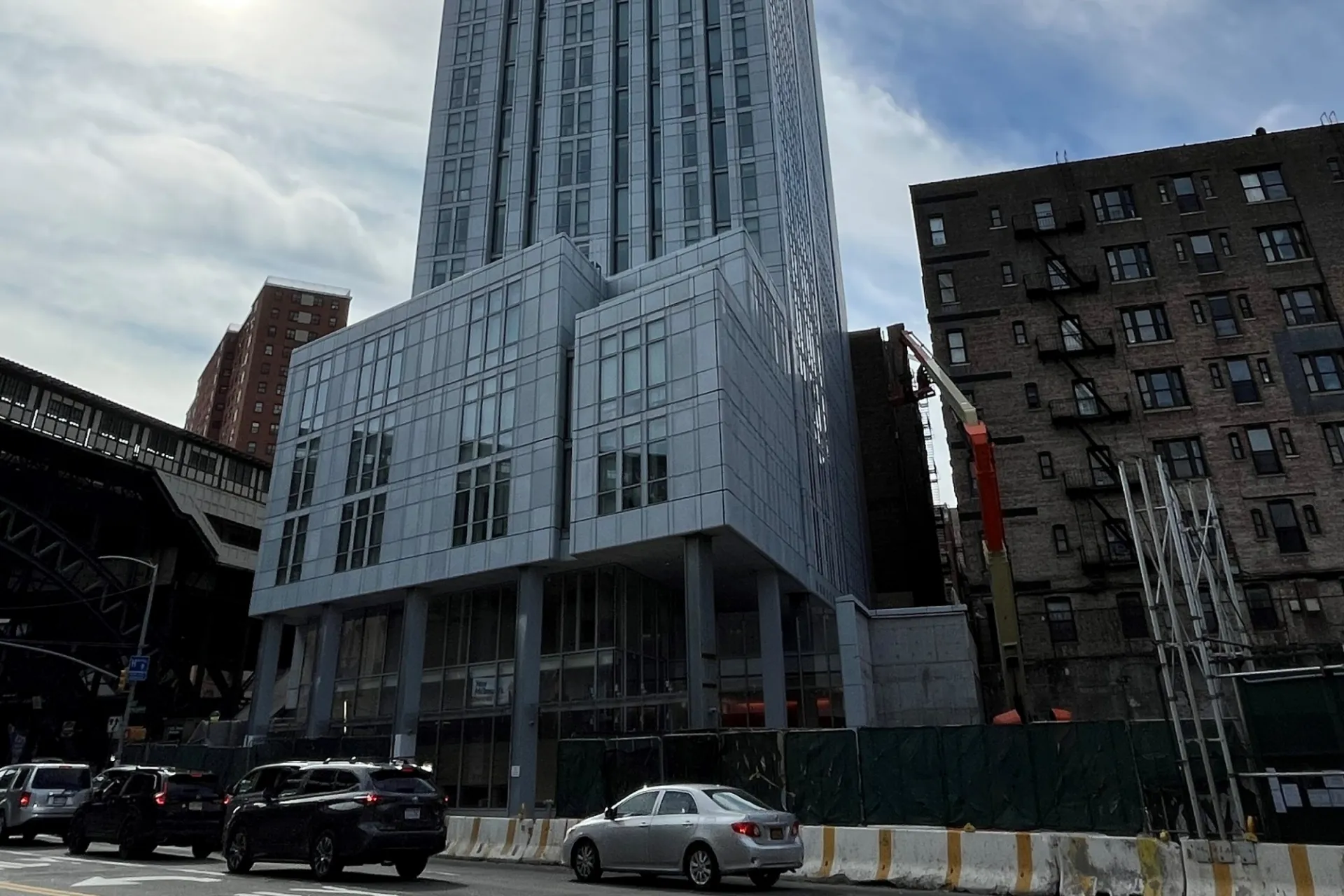 A view of the lower floors of 600 W. 125th Street, with cars waiting at an intersection in front.