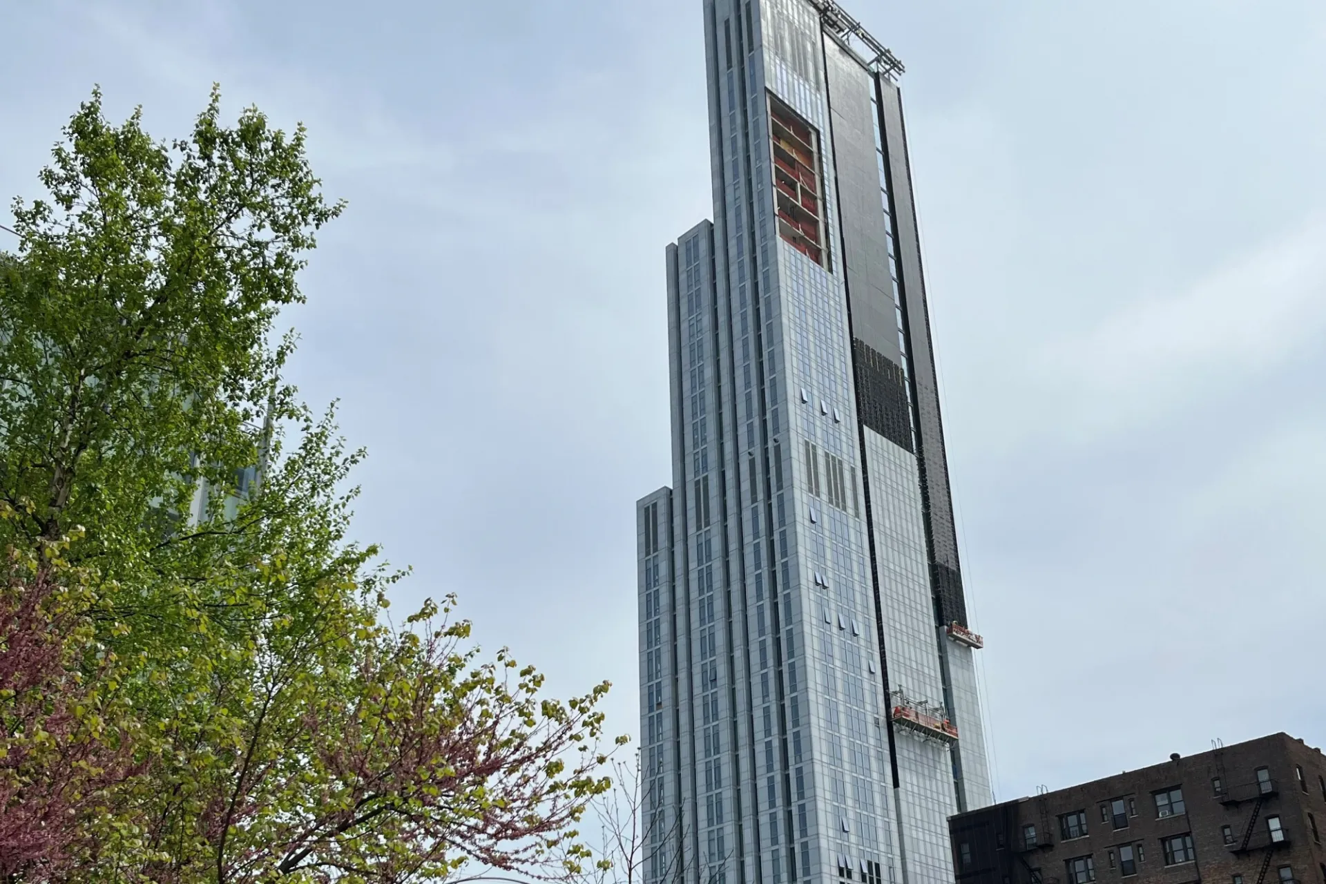 A view of the upper floors of 600 W. 125th Street on a sunny day with a tree in the forefront. 