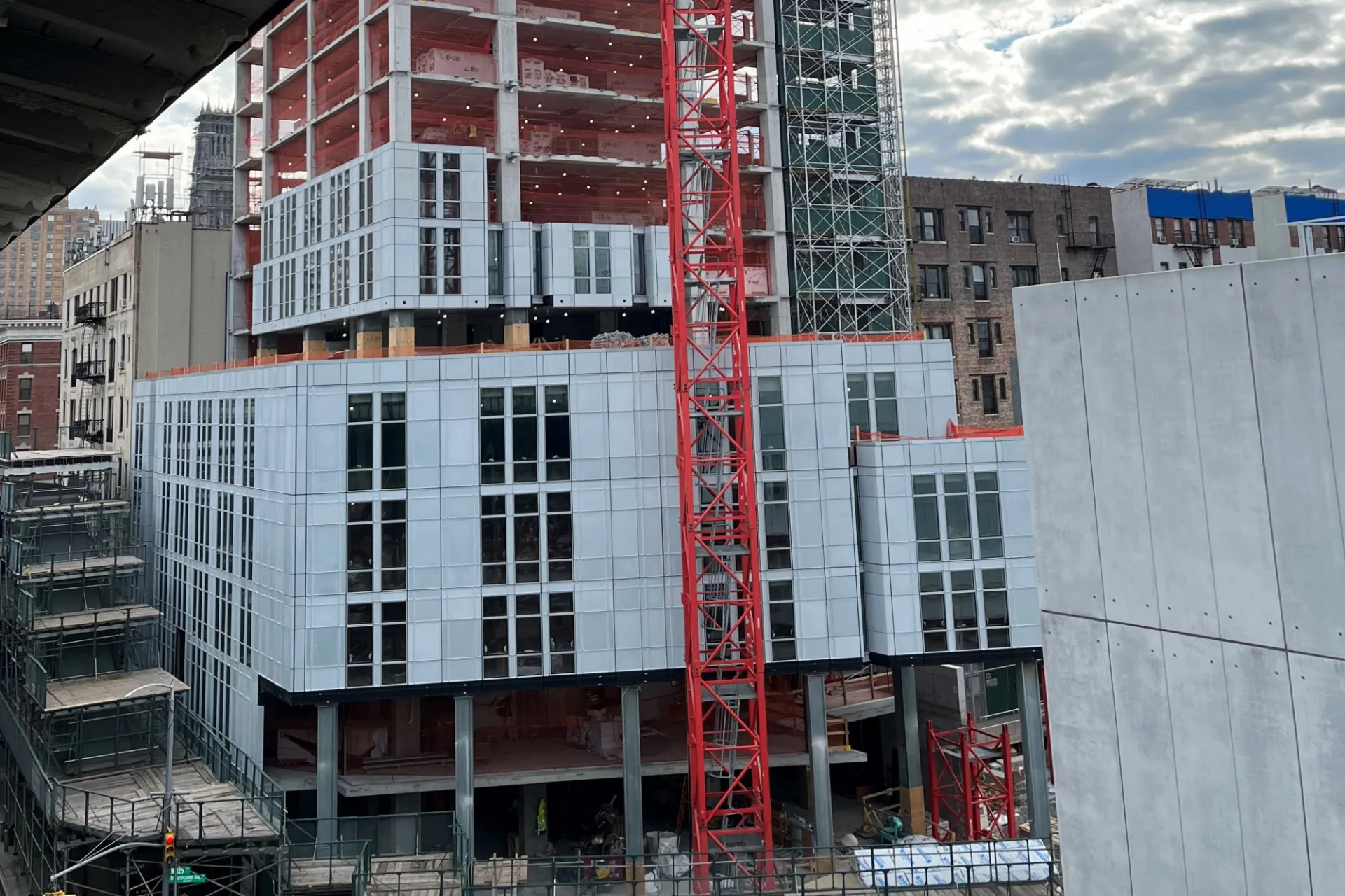 A view of the 600 W. 125th Street construction site near the street level, which has facade panels installed around it.