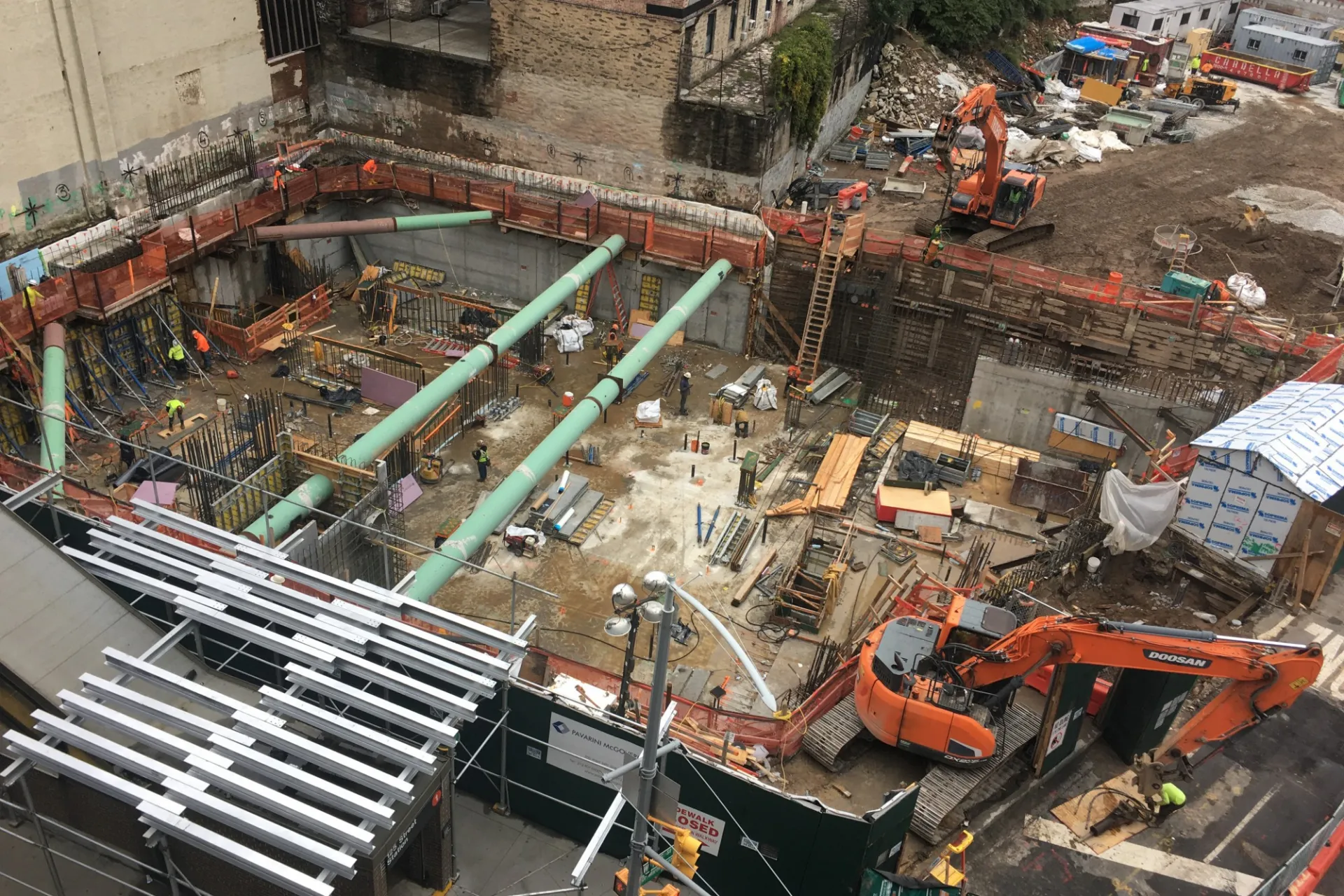 A aerial view of the 600 W. 125th Street construction site, full of materials and large green pipes running overhead.  ﻿