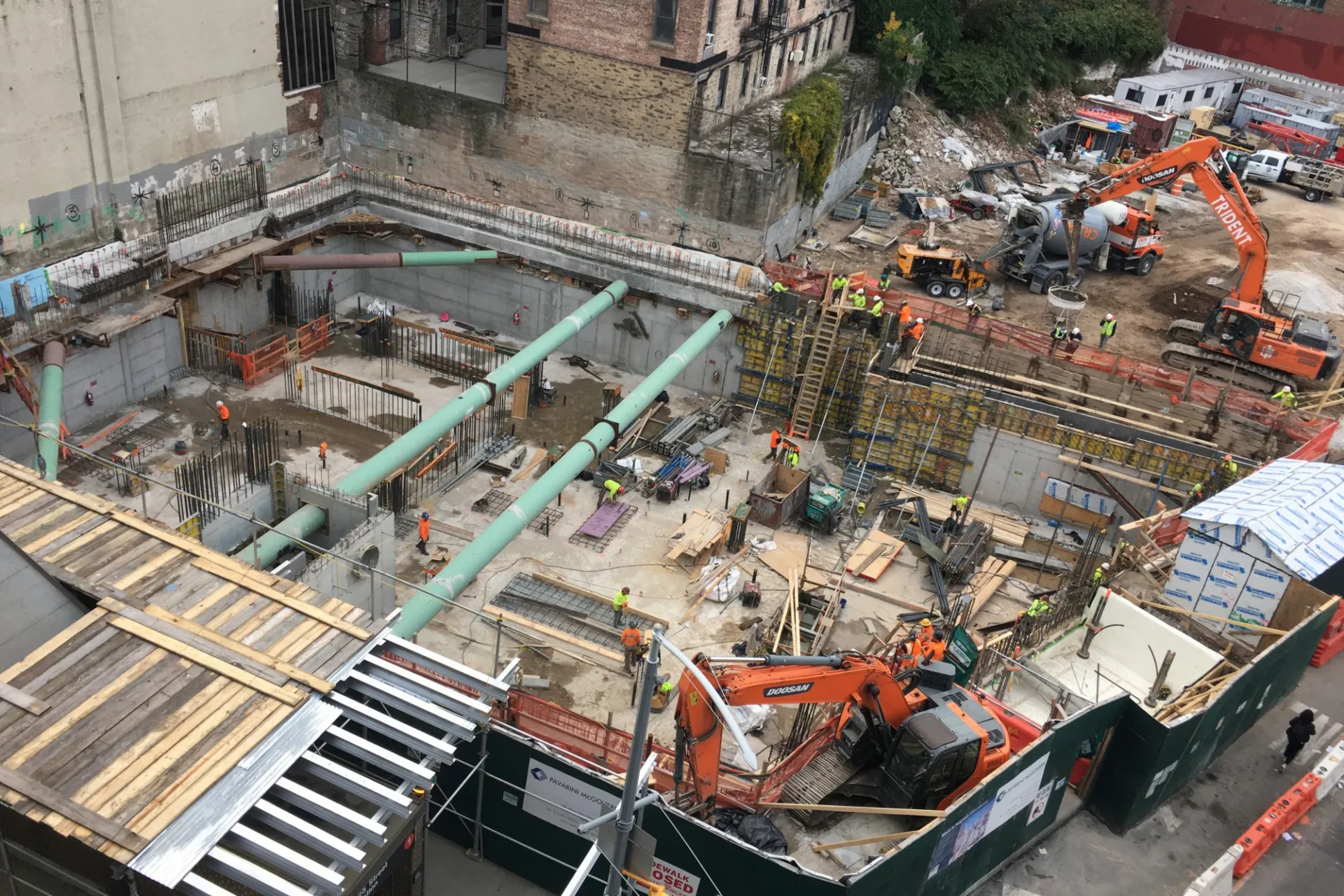 A aerial view of the 600 W. 125th Street construction site, full of materials and large green pipes running overhead.  ﻿
