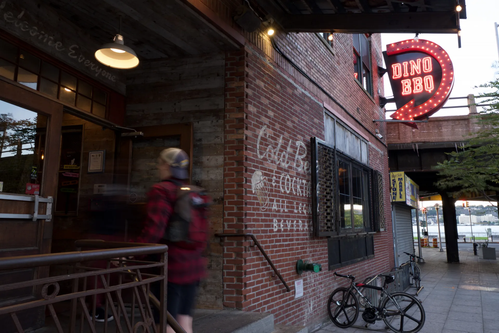 A patron walks into the entrance to Dinosaur Bar-B-Que, which is a brick facade building.