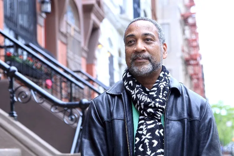 John Reddick wearing a black and white scarf and a leather jacket on a street in Harlem.