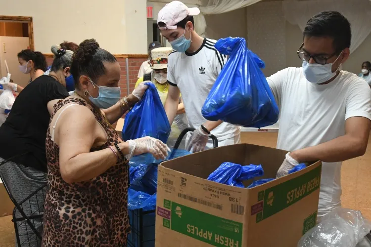 Masked men and women put bags of food into boxes.