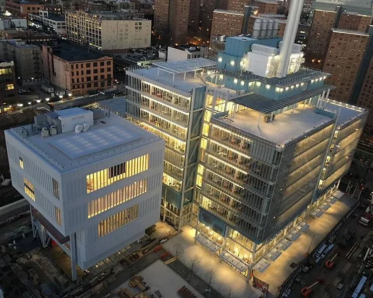 The Lenfest Center for the Arts and the Jerome L. Greene Science Center lit up at night, surrounded by other buildings in the area.