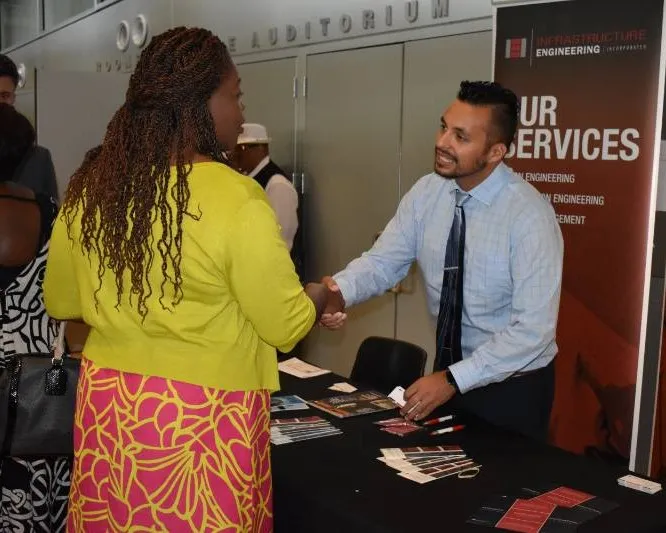A man representing a company shakes a visitor's hand.