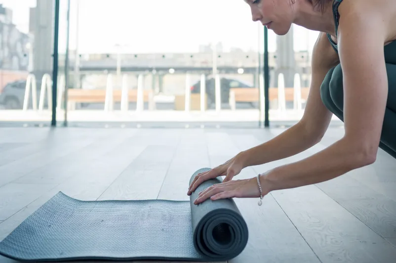 A person unrolls a yoga mat in Method Collective.