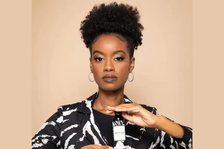 African American woman with afro holding a Youmas Beauty product.