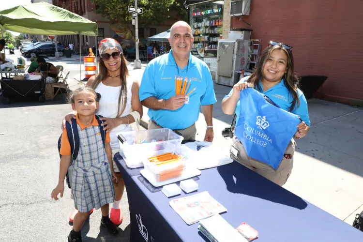 Ricardo Morales, Assistant Director of Community Engagement at Columbia University’s Department of Public Safety, poses with a team member and attendees at the 11th Annual "Back-2-School" Block Party in Harlem. Photo credit: Michael DiVito