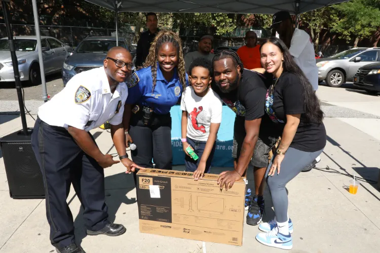 Members of the NYPD 26th Precinct’s Community Affairs division and local volunteers pose with an attendee at the 11th Annual "Back-2-School" Block Party in Harlem. Photo credit: Michael DiVito