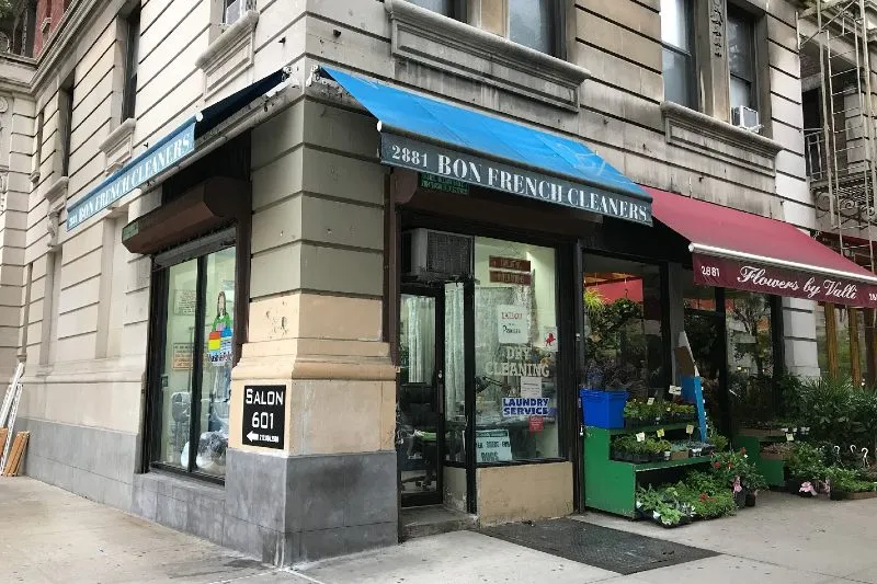 A building with a blue awning saying "Bon French Cleaners."