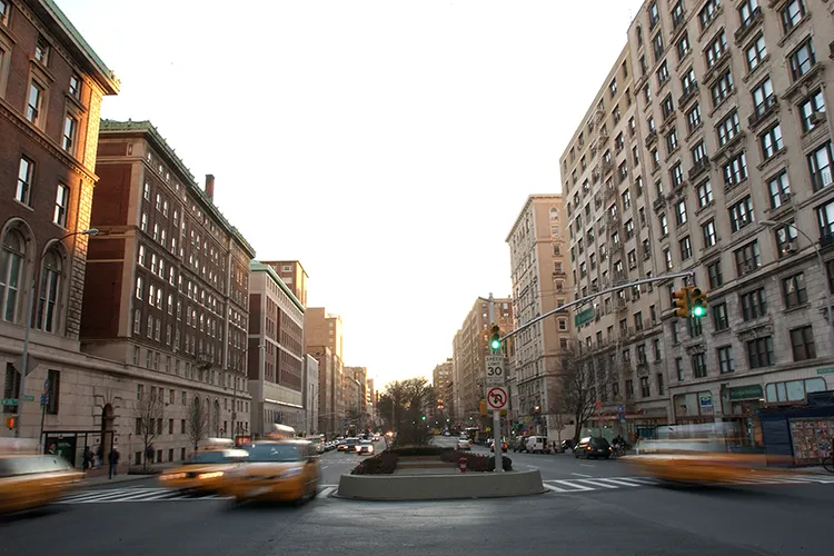 Photo of Broadway with blurry vehicles and tall residential buildings.