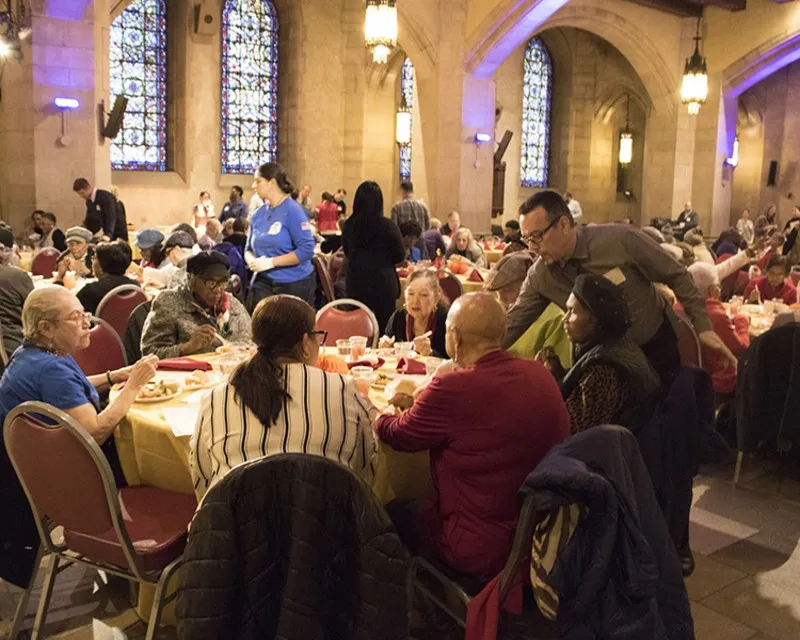 Seniors seated at tables eating a Thanksgiving meal