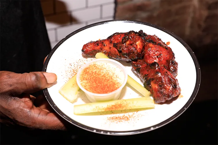 A plate of chicken wings, celery, and dipping sauce. 