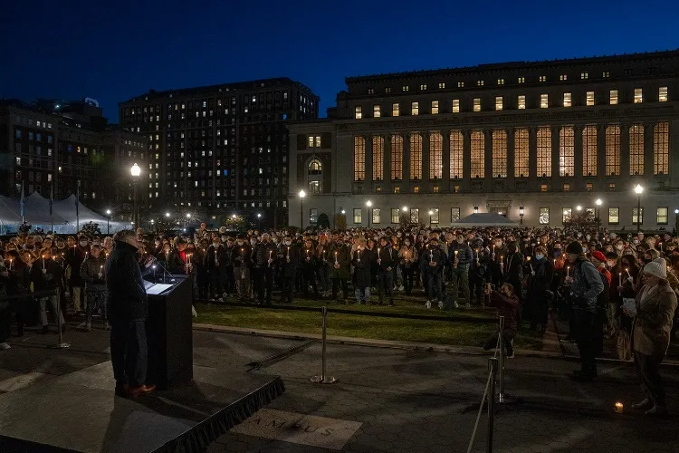 Person at podium overseeing a large crowd of people outdoors.