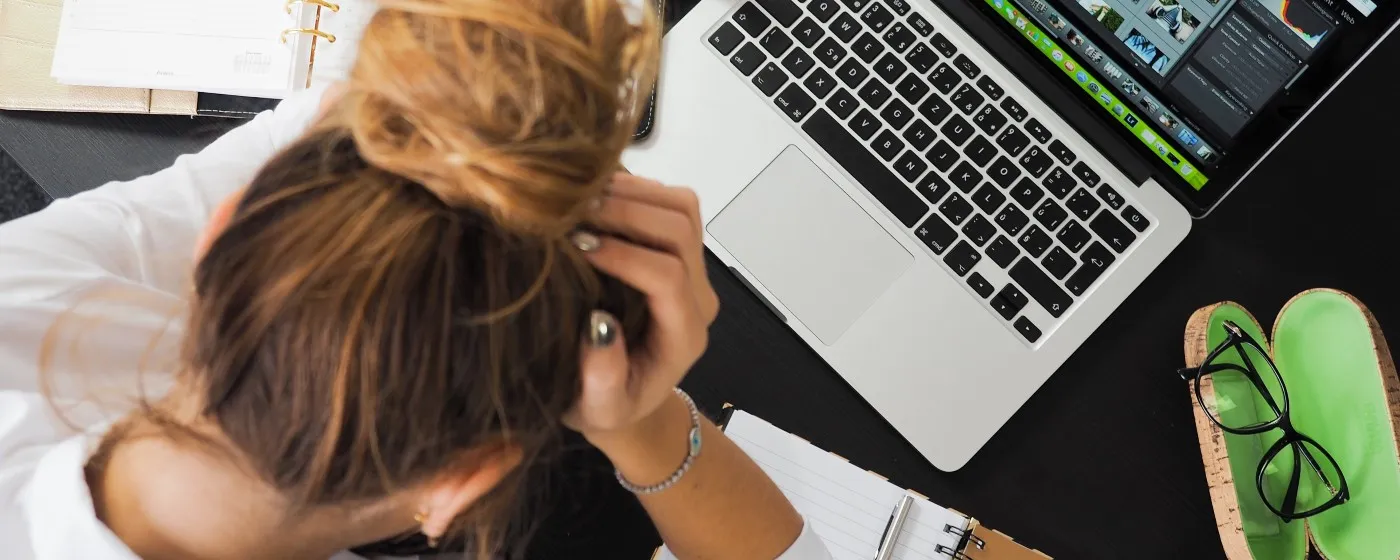 Frustrated woman looking at her computer with her hand on her face.