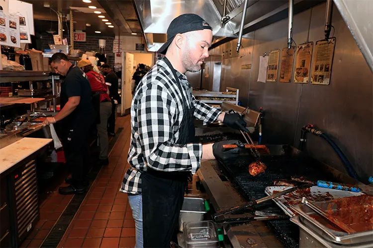 A Dinosaur Bar-B-Que employee preps chicken on the grill. 