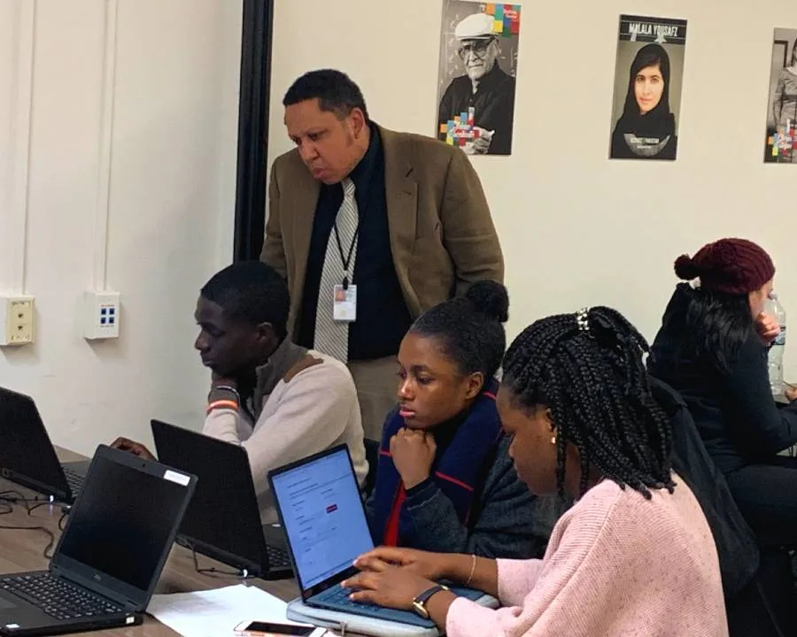 A man gets assistance with his census taker application while others complete the applications by themselves in the foreground.