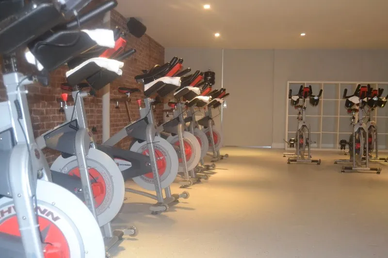 A row of exercise bicycles in front of a brick wall.