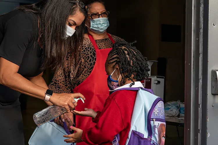 An adult pumps hand sanitizer into a child's hand.