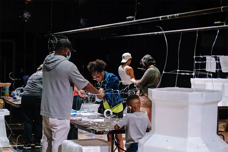 A family works on the wiring for a latern in Miller Theatre. 