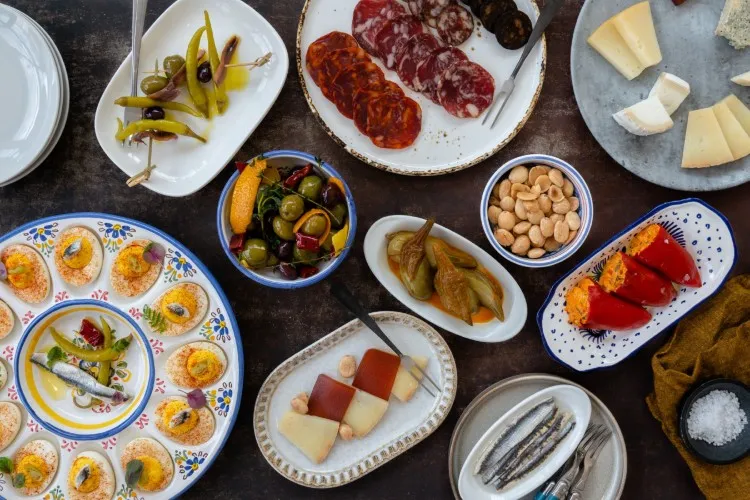 Plates of food including cured meats, cheese, deviled eggs, and peppers on a table.